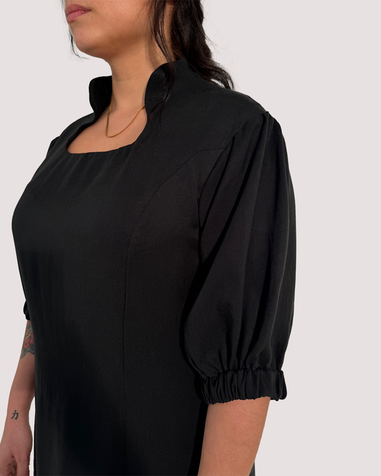 Seitenansicht eines schwarzen Kleids aus Lyocell, mit angeschnittenem Stehkragen und Wienernähten.