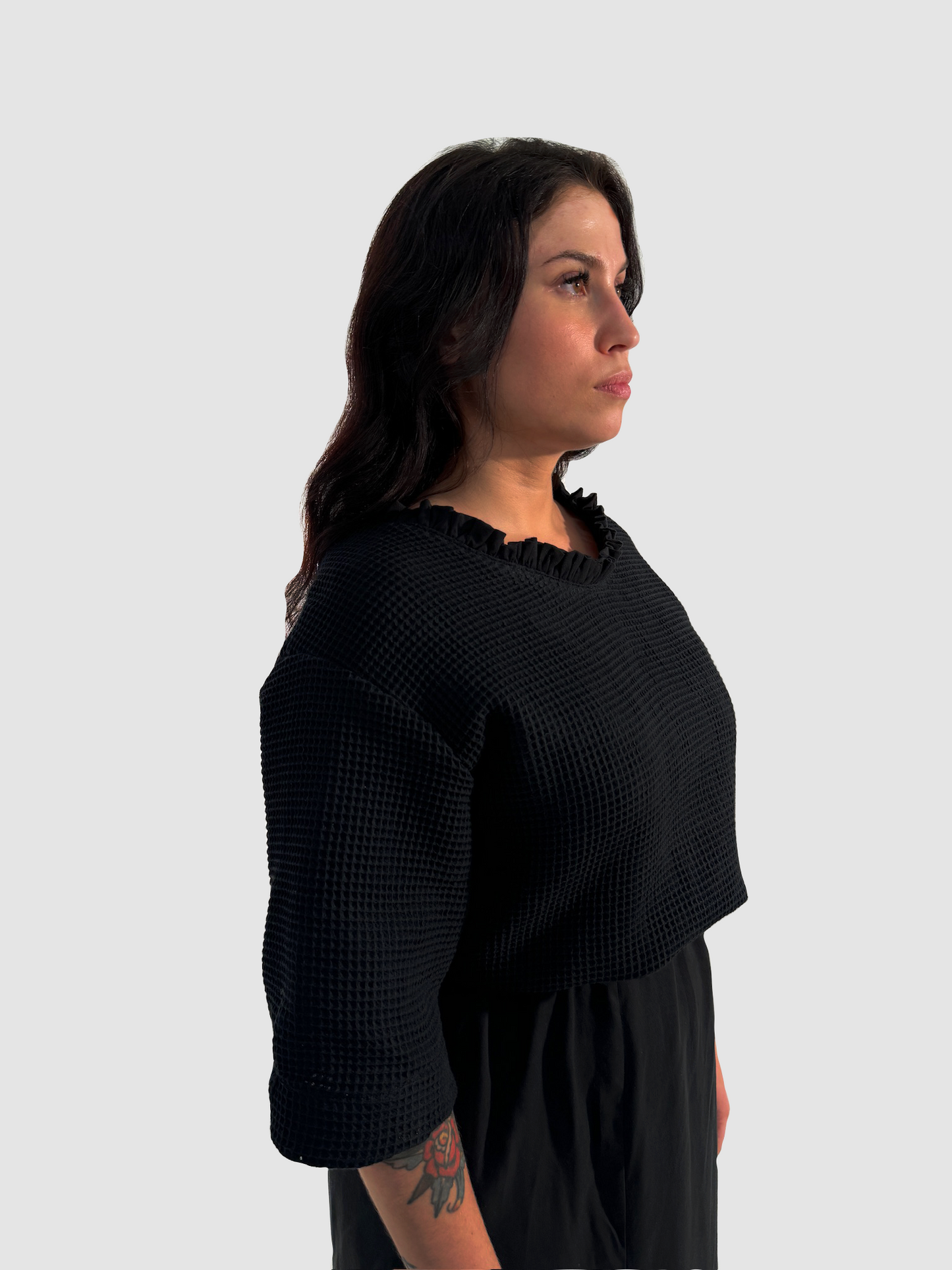 Seitenansicht eines schwarzen Shirts aus Waffelpique, mit gerüschtem Einsatz am Halsausschnitt aus Lyocell.