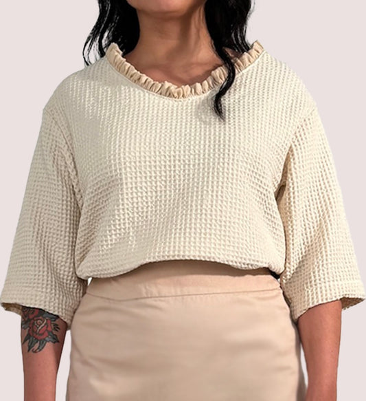 Vorderansicht eines beigen Shirts aus Waffelpique, mit gerüschtem Einsatz am Halsausschnitt aus Lyocell.