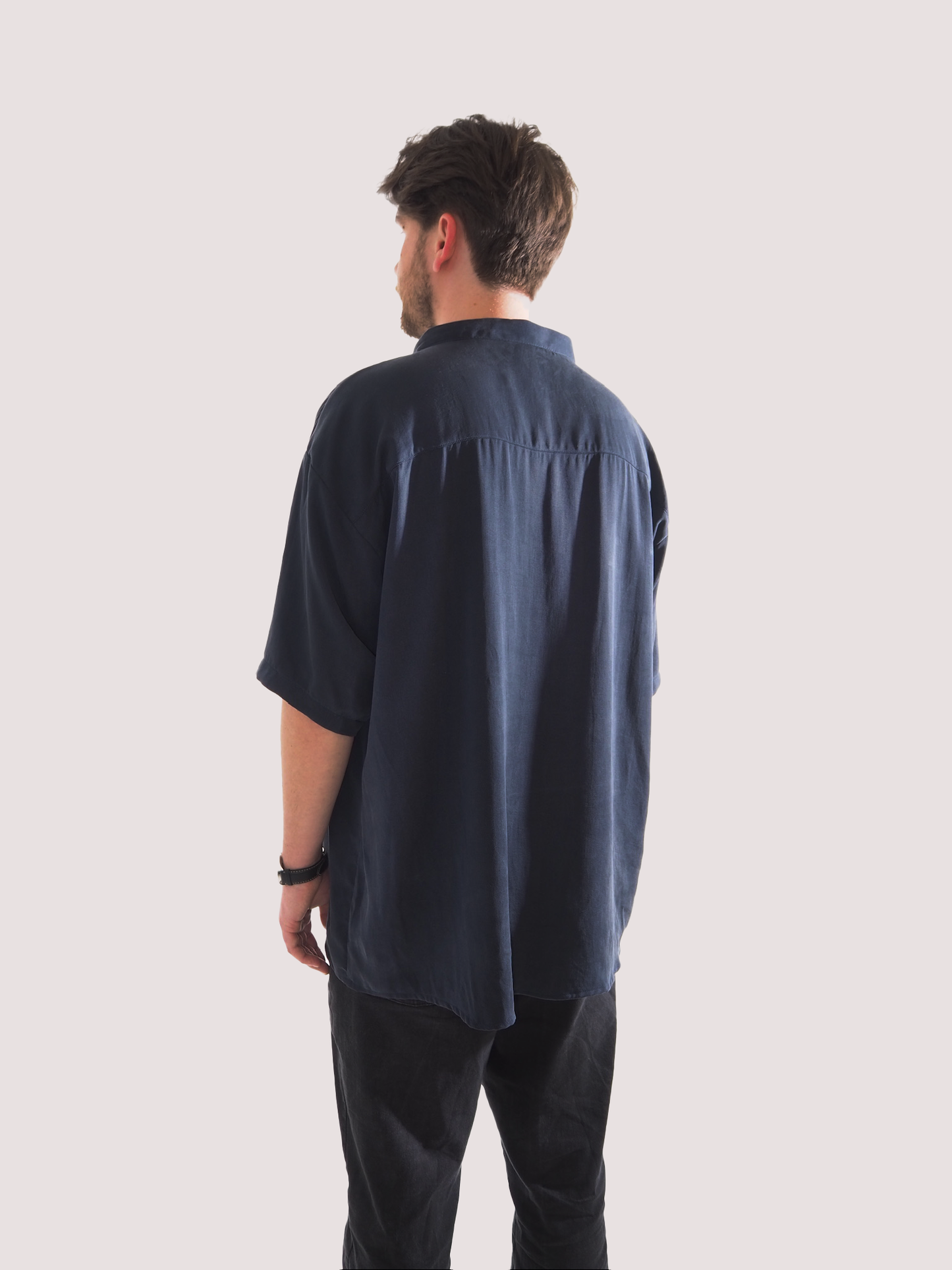 Rückansicht eines Hemds aus Lyocell, mit Stehkragen und zwei Knöpfen aus Recycling-Baumwolle.