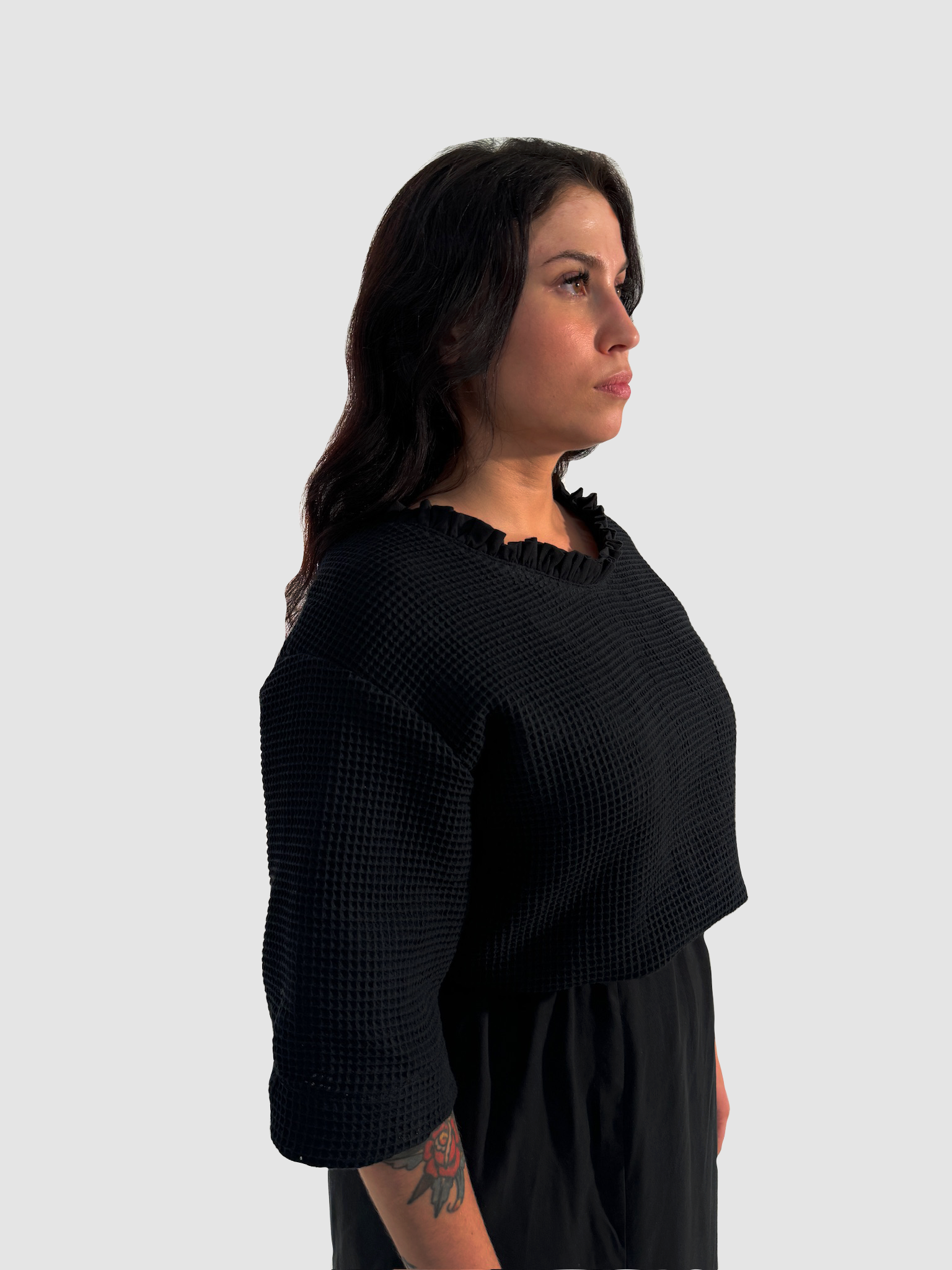Seitenansicht eines schwarzen Shirts aus Waffelpique, mit gerüschtem Einsatz am Halsausschnitt aus Lyocell.