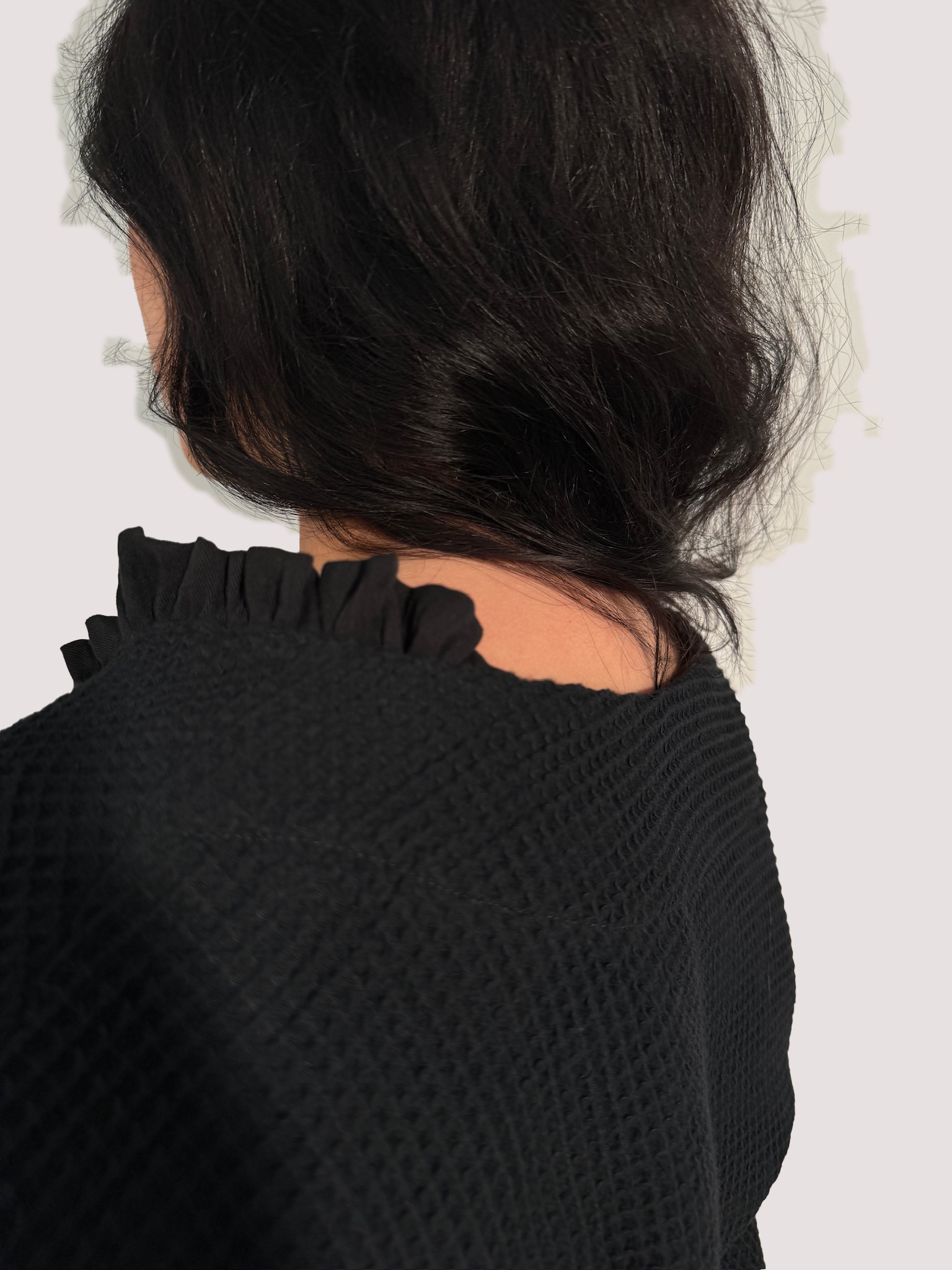 Rückansicht eines schwarzen Shirts aus Waffelpique, mit gerüschtem Einsatz am Halsausschnitt aus Lyocell.
