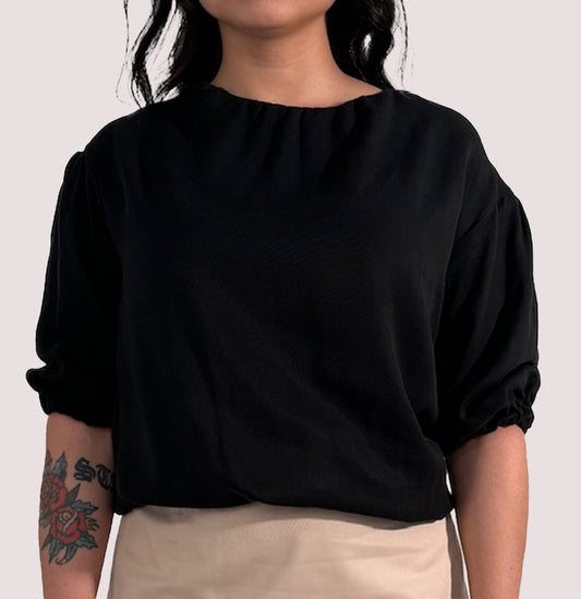 Vorderansicht eines schwarzen Shirts, mit elastischen Säumen, aus Lyocell.
