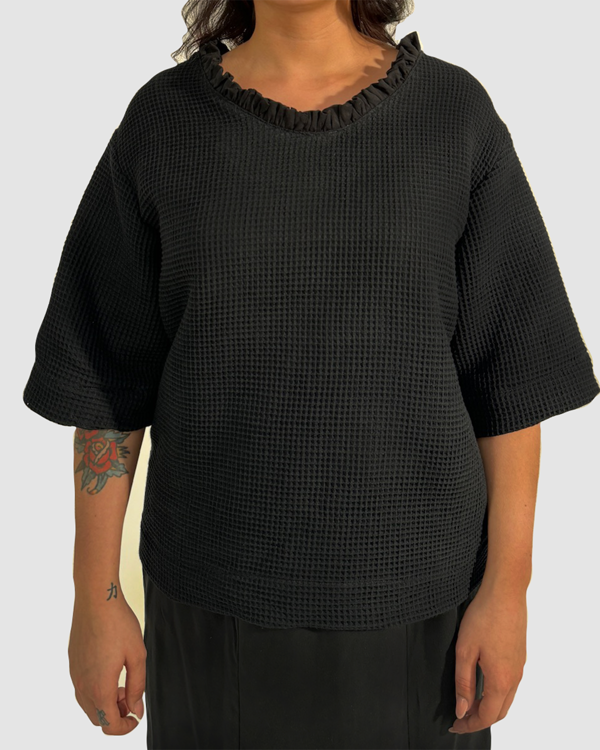 Vorderansicht eines schwarzen Shirts aus Waffelpique, mit gerüschtem Einsatz am Halsausschnitt aus Lyocell.